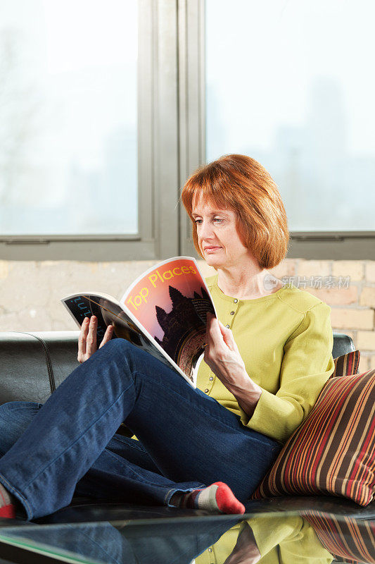 Adult Woman Relaxing and Reading Magazine in Condominium Home Vt .成年妇女放松和阅读杂志